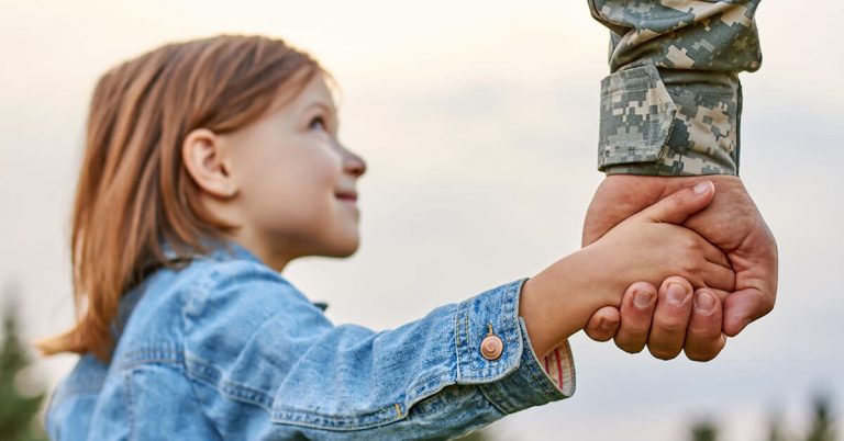 A father in the military holding hands with his daughter.