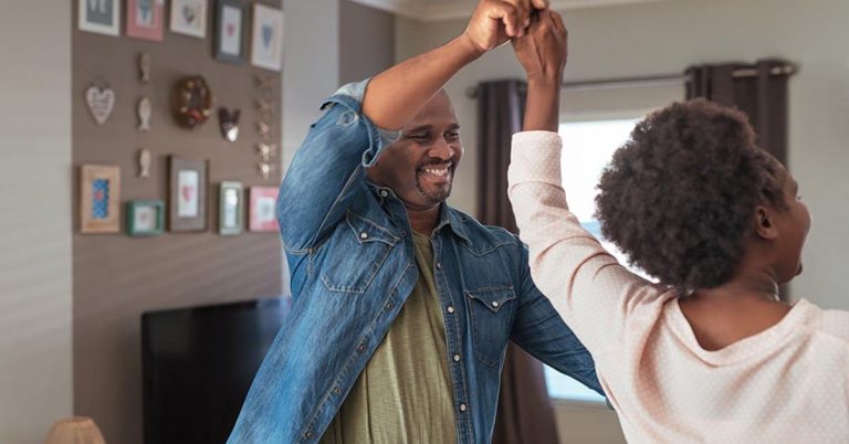 A couple dance in their living room.