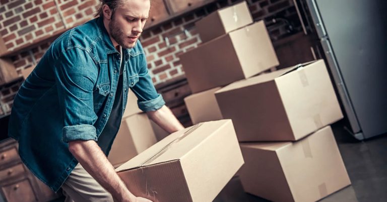 Man moving cardboard boxes into stacked piles