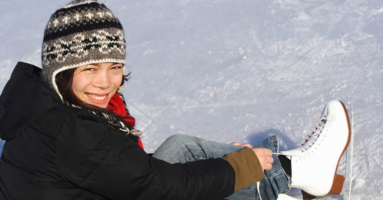 A woman smiles as she ties her ice skates.